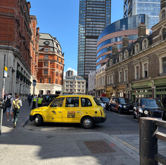 a view of central London including a yellow taxi and some historic buildings 