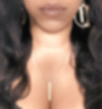 Woman wearing gold bar necklace and large hoop earrings