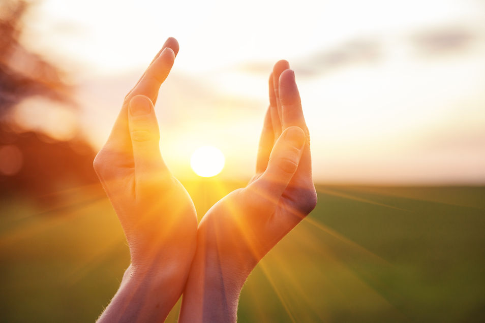 young woman raising hands praying at sunset or sunrise light.jpg