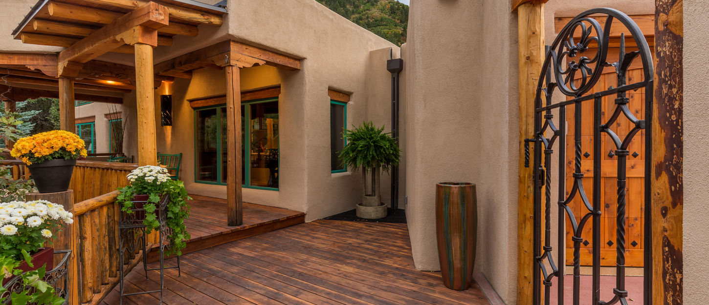 Courtyard entry with stucco walls, wood beams, and landscaped planters leading to the home entrance.