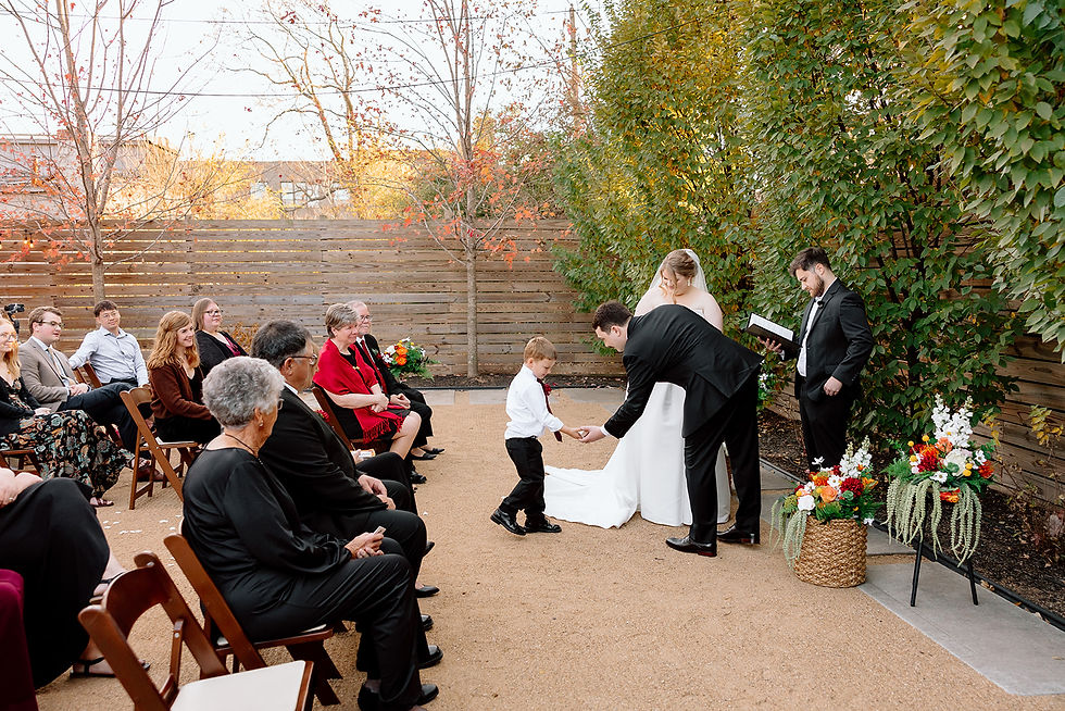 Emily and Mikel's young ring bearer hands over the rings during their intimate wedding ceremony at The Fire House KC in Kansas City.
