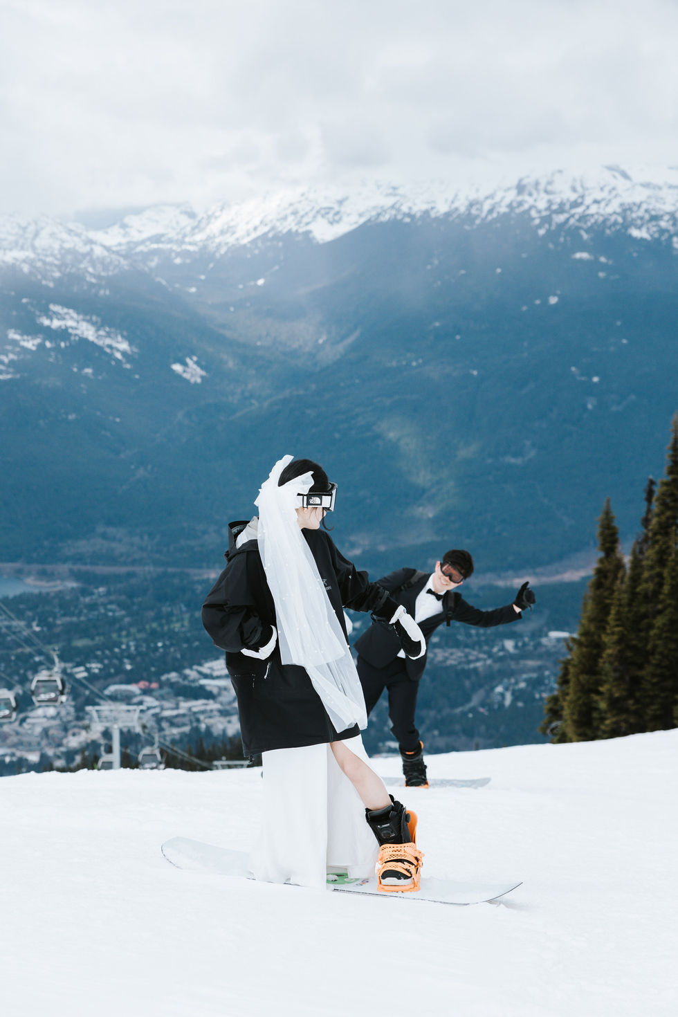  Engaged couple snowboarding down the slopes with the groom smiling lovingly at the bride at Whistler Blackcomb — joyful and adventurous winter engagement moment.​​​​​​​​​​​​​​​​