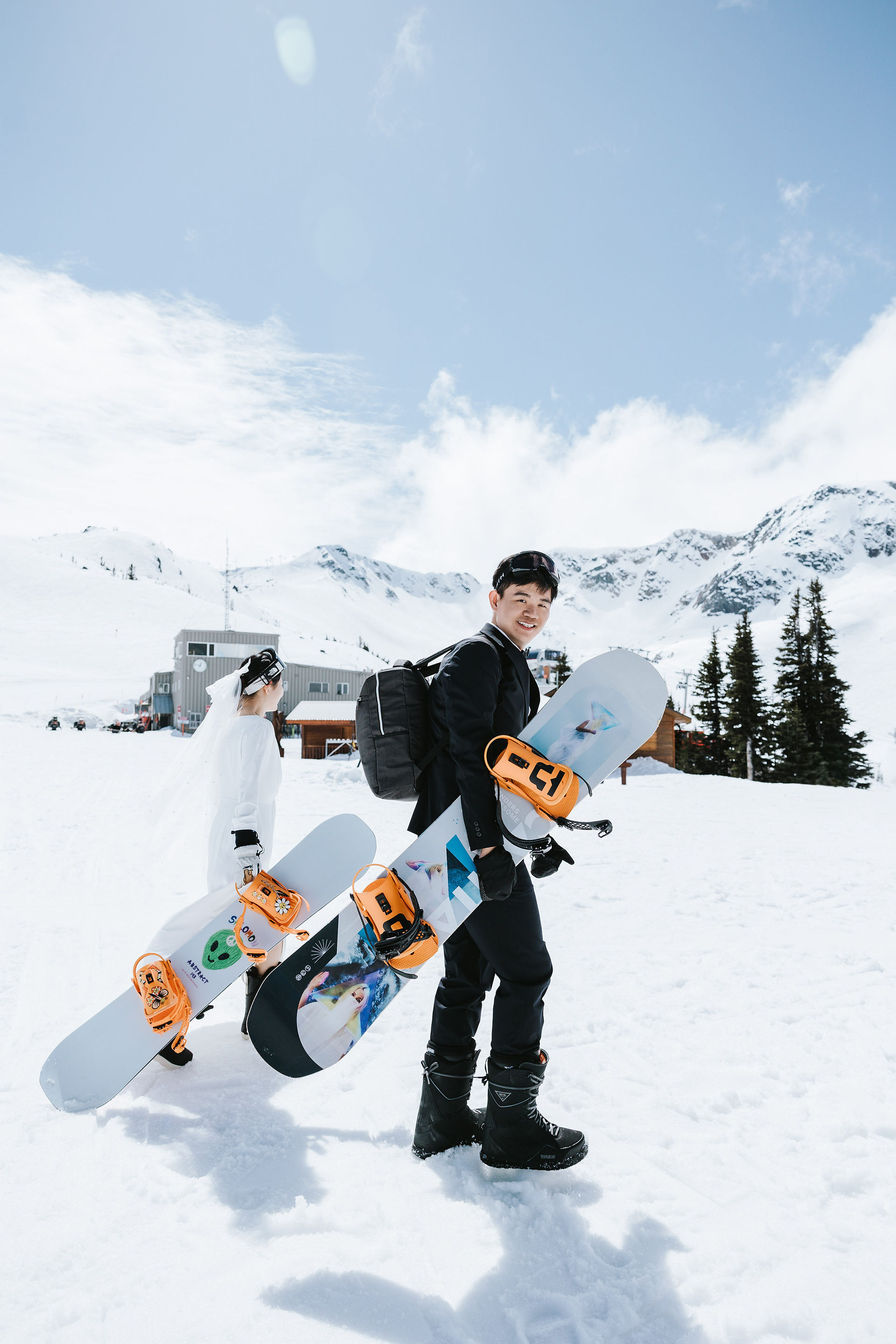  Engaged couple carrying their snowboards as they hike up the mountain at Whistler Blackcomb — adventurous and scenic snowboard engagement moment.​​​​​​​​​​​​​​​​