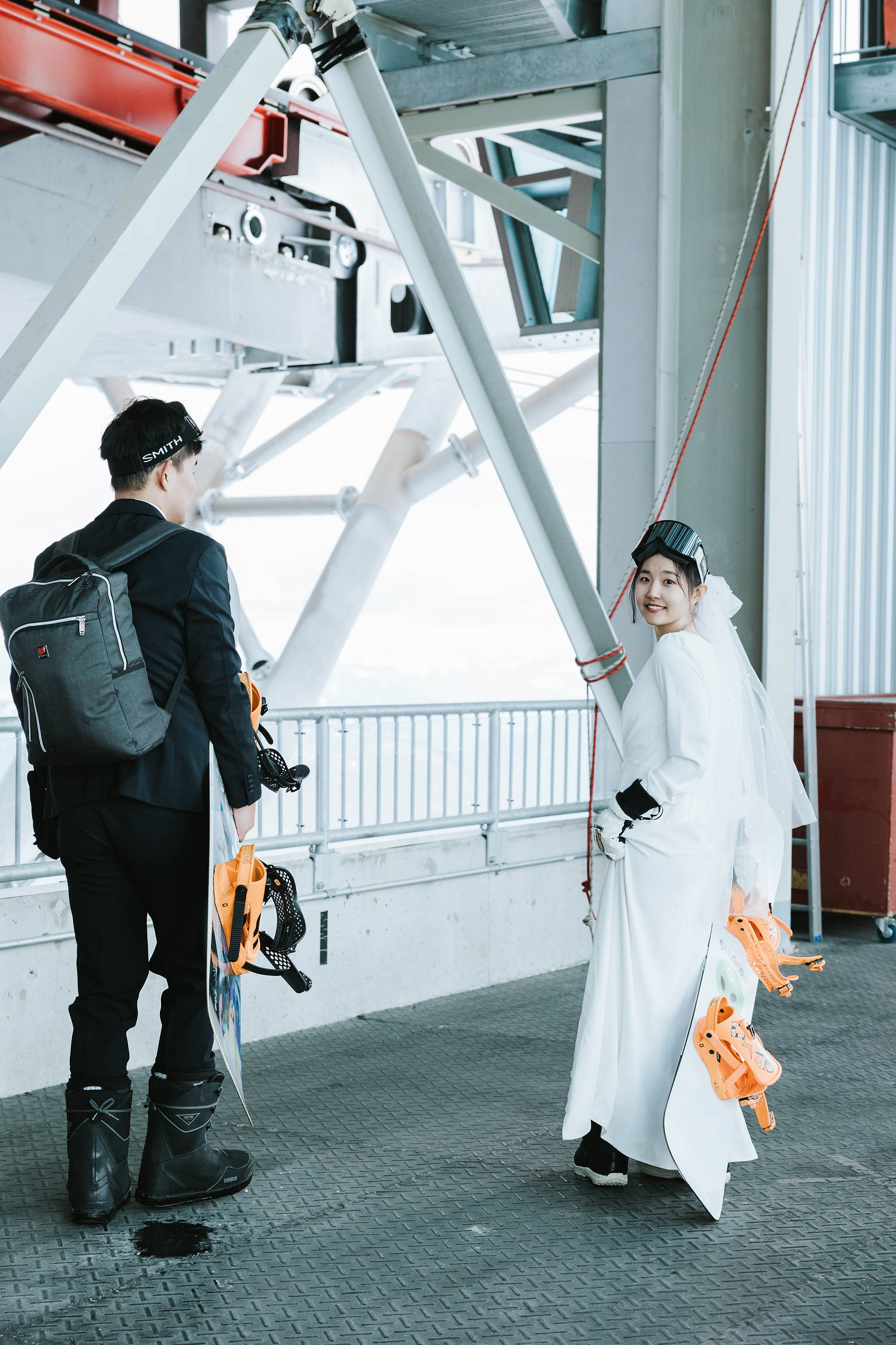  Engaged couple stepping off the gondola at Whistler Blackcomb — the groom walking ahead while the bride glances back — candid and cinematic snowboard engagement moment.​​​​​​​​​​​​​​​​