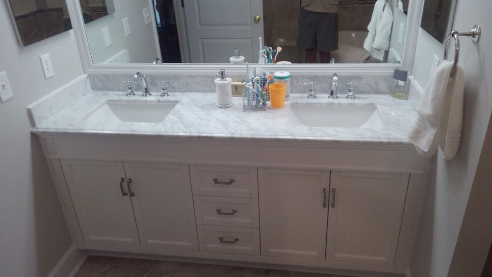 a white bathroom counter top with square sinks and silver fixtures