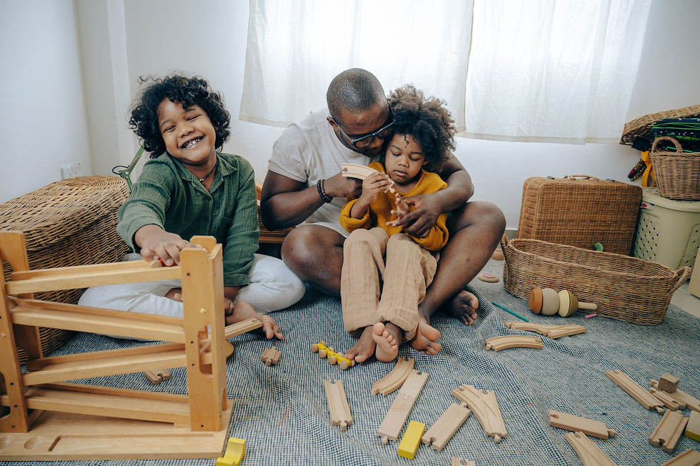 a man sitting with two small children playing with blocks