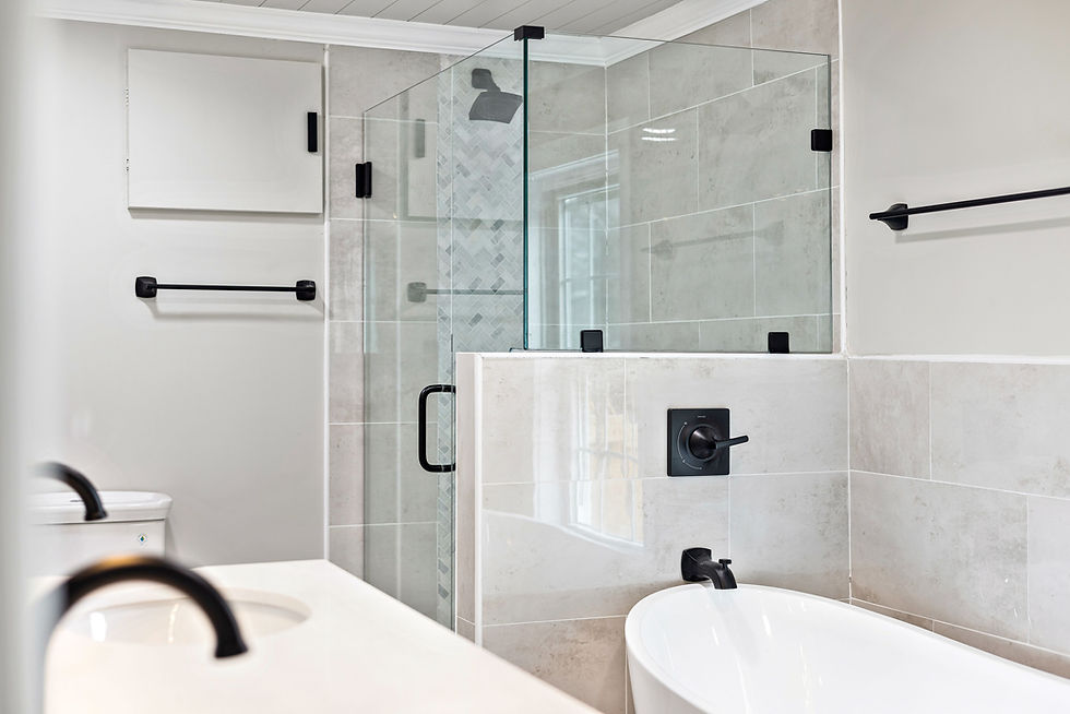 a new bathroom, crisp white with black fixtures with a glass shower and white standalone tub