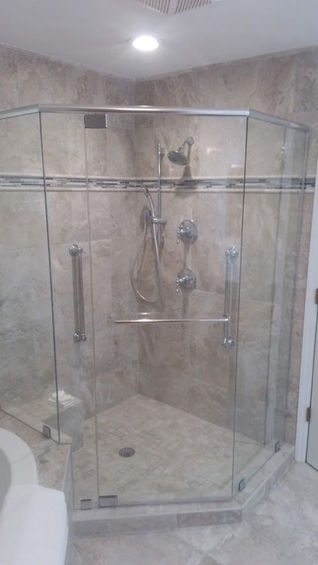 large glass shower with gray tiles and silver fixtures