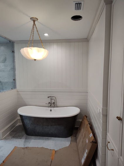 Bathroom with painted beadboard walls, a freestanding dark-finish tub, and a vintage hanging light