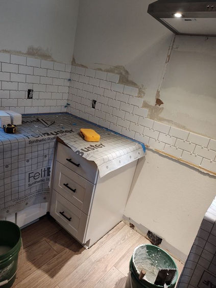 kitchen remodel with tiles being removed and the counters covered with construction paper