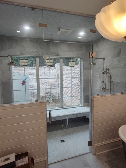 a large two headed shower with half walls and glass
