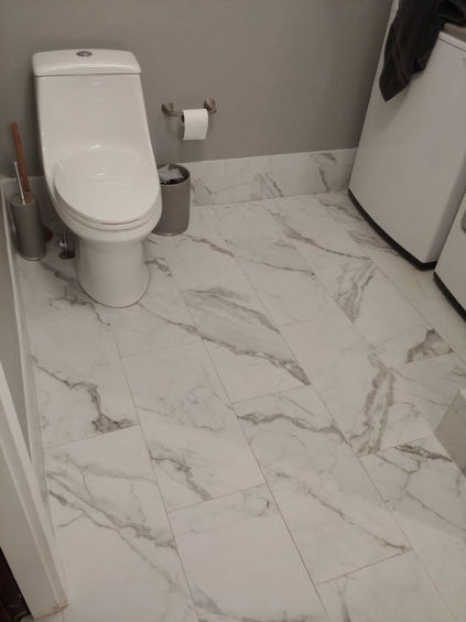 white marble flooring around a toilet with a white washer and dryer off to the side