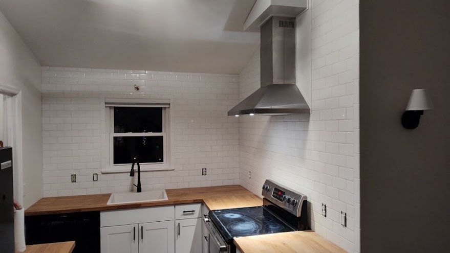 white subway tile with wooden counter tops and a stainless steel range hood