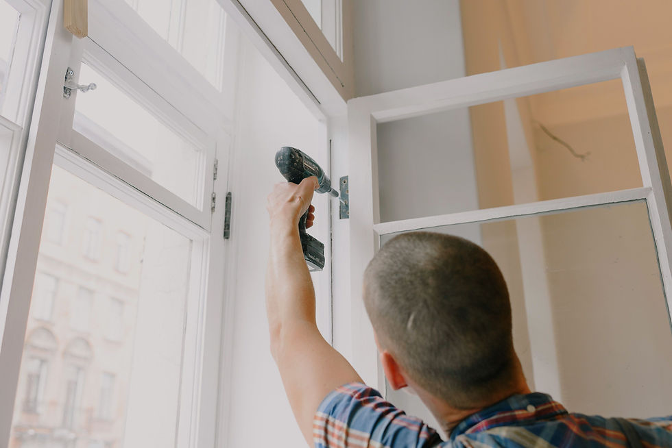 construction worker screwing a screw into a window panel with a drill