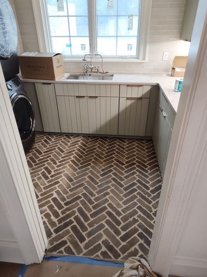 herringbone designed darkl gray tiles with white grouting, clapboard counters and a silver sink