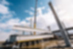 Crane lifting concrete beam from truck at construction site