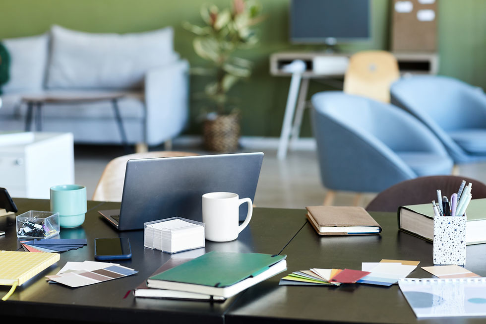 Cluttered modern office desk with laptop, notebooks, mug, and phone.