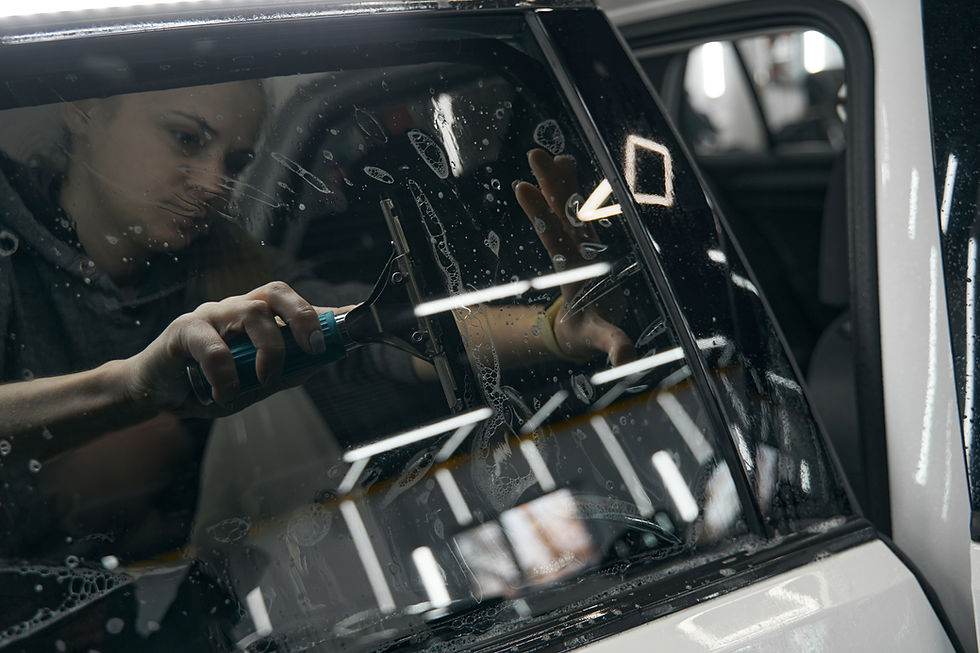 Person professionally applying tint film onto a car's side window.