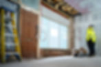 Worker inspects room under renovation, ladder, exposed ceiling