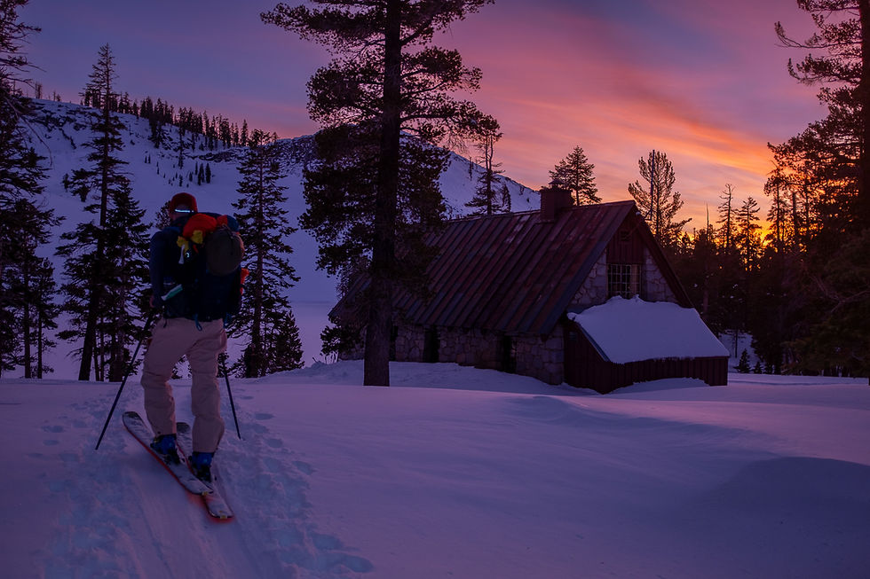 Man skiing into the Ostrander Ski Hut at sunset