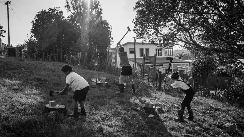 children split wood with axes