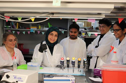 Grad students smiling around lab bench