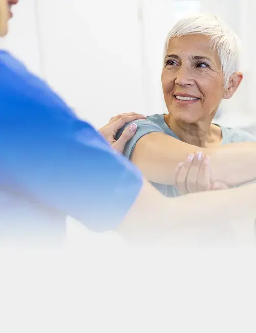 Physiotherapist supporting an older patient with a gentle arm stretch during tendon rehabilitation