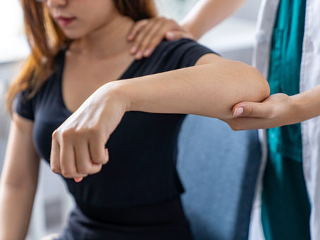 Office worker wincing while gripping a mug with outer elbow pain from tennis elbow, City of London