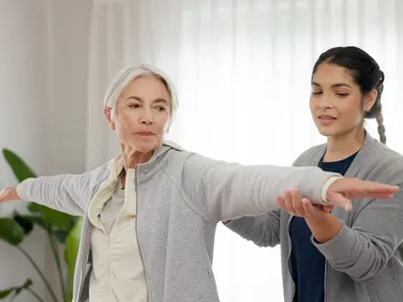 Physiotherapist supporting an older woman with balance and arm movement exercises during Parkinson’s physiotherapy in London