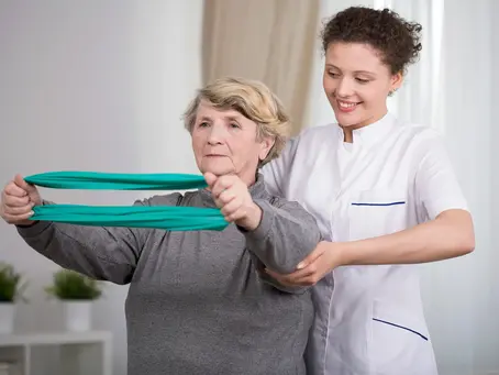 Physiotherapist guiding an older woman performing resistance band exercises during vestibular physiotherapy for balance and dizziness.