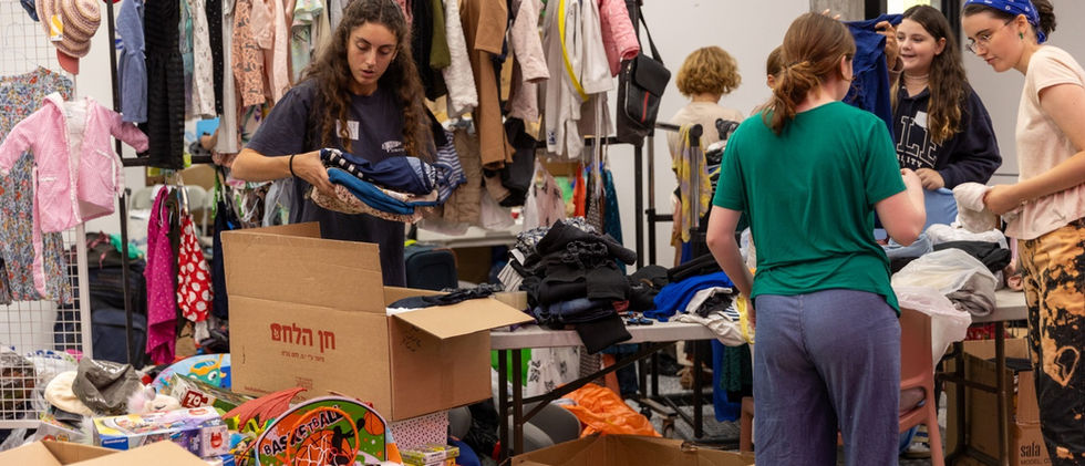 Volunteers sorting and folding clothing in an indoor relief center.