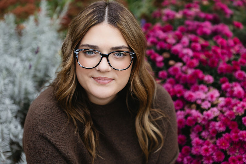 Senior Pictures  of a girl wearing glasses in front of flowers at the Canfield Fairgrounds. 