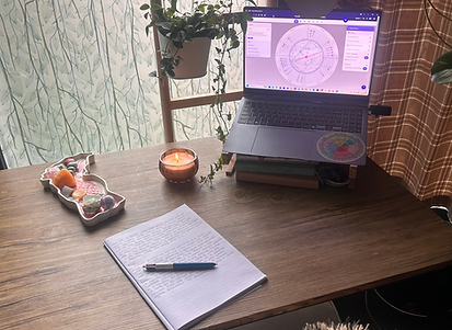 Astrology workspace with laptop showing a birth chart, candle, and crystals, representing Moon & Soul Coaching’s blend of psy