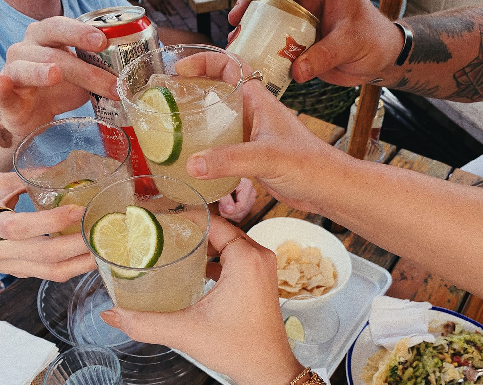 Group of travelers toasting with their drinks over a table full of food.