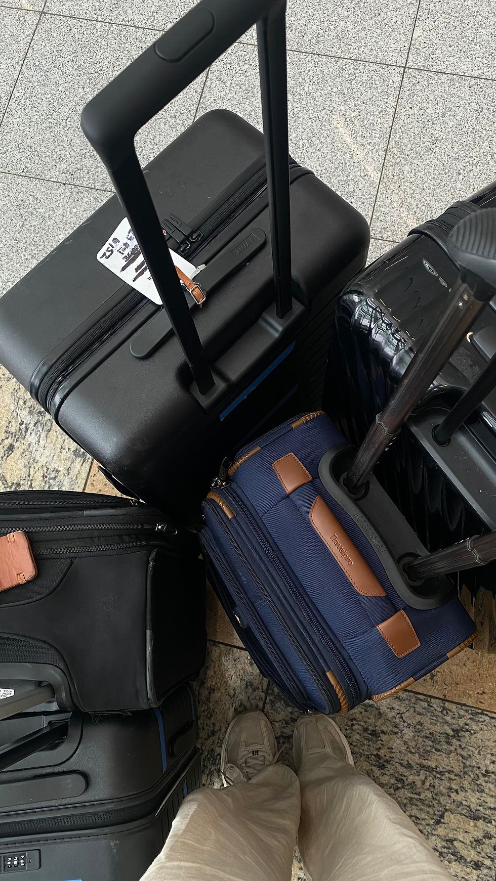 Selfie of a person's legs and a couple of luggage at the airport.