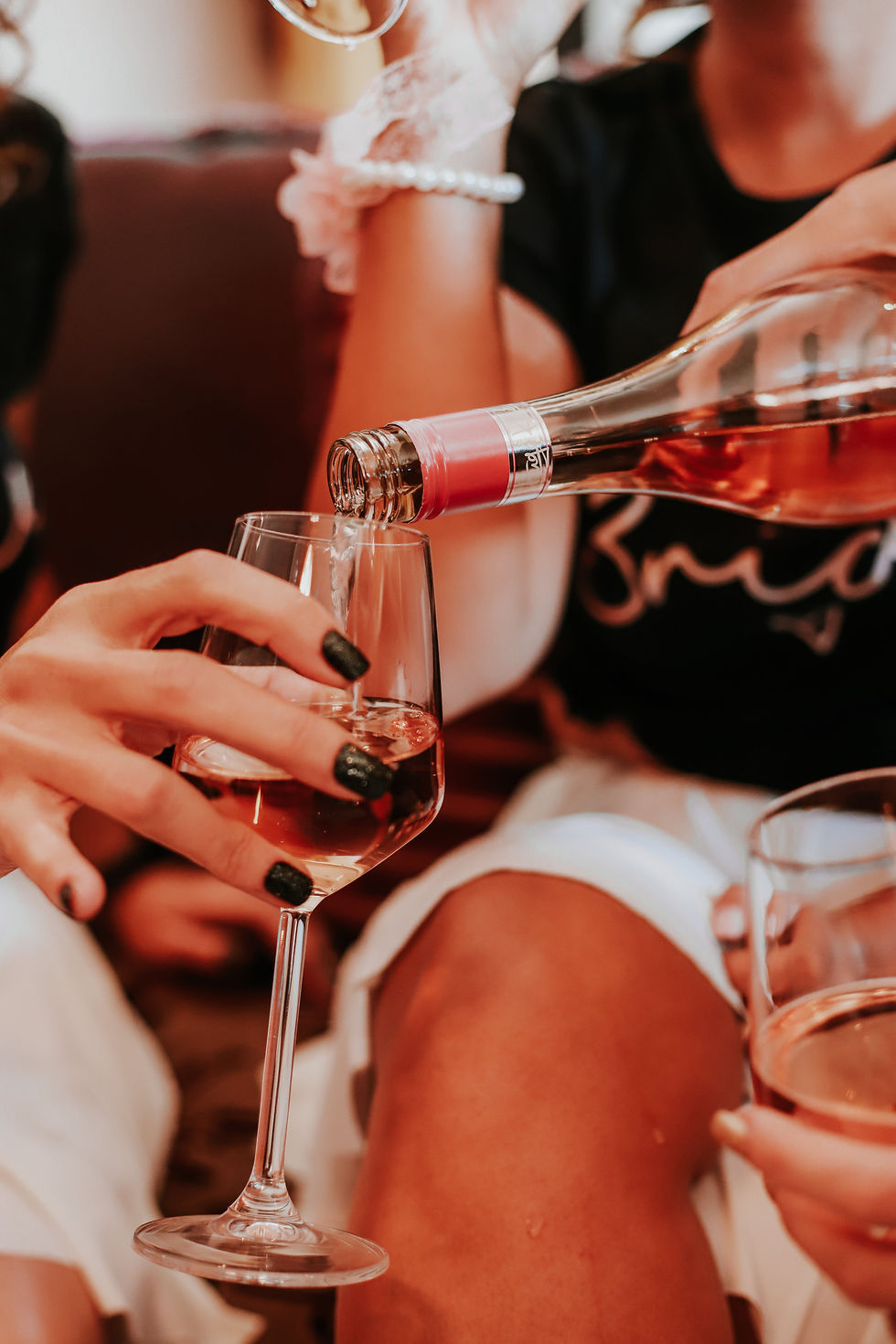 Rose being poured into a glass surrounded by women at a bachelorette party.