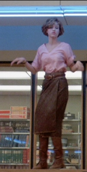 Molly Ringwald in The Breakfast Club wearing a long brown skirt with a brown belt and a pink sweater top. 