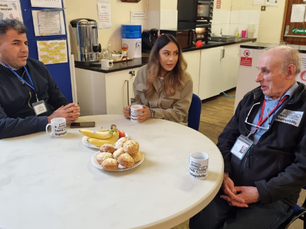 Three people around a table chatting and drinking tea