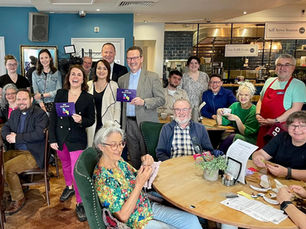 Group of people posing around BBC journalist Nina Warhurst in Saints Nuneaton café