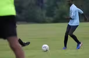 3 men playing football on a football pitch