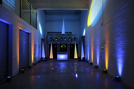 Voller Aufbau von Licht mit Moving Heads, Strahlern und Pyramiden hinter einem DJ-Tisch.