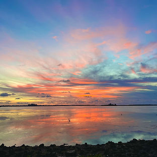 A vibrant sunset over the water, representing the beauty of nature and reflection after a day's work.
