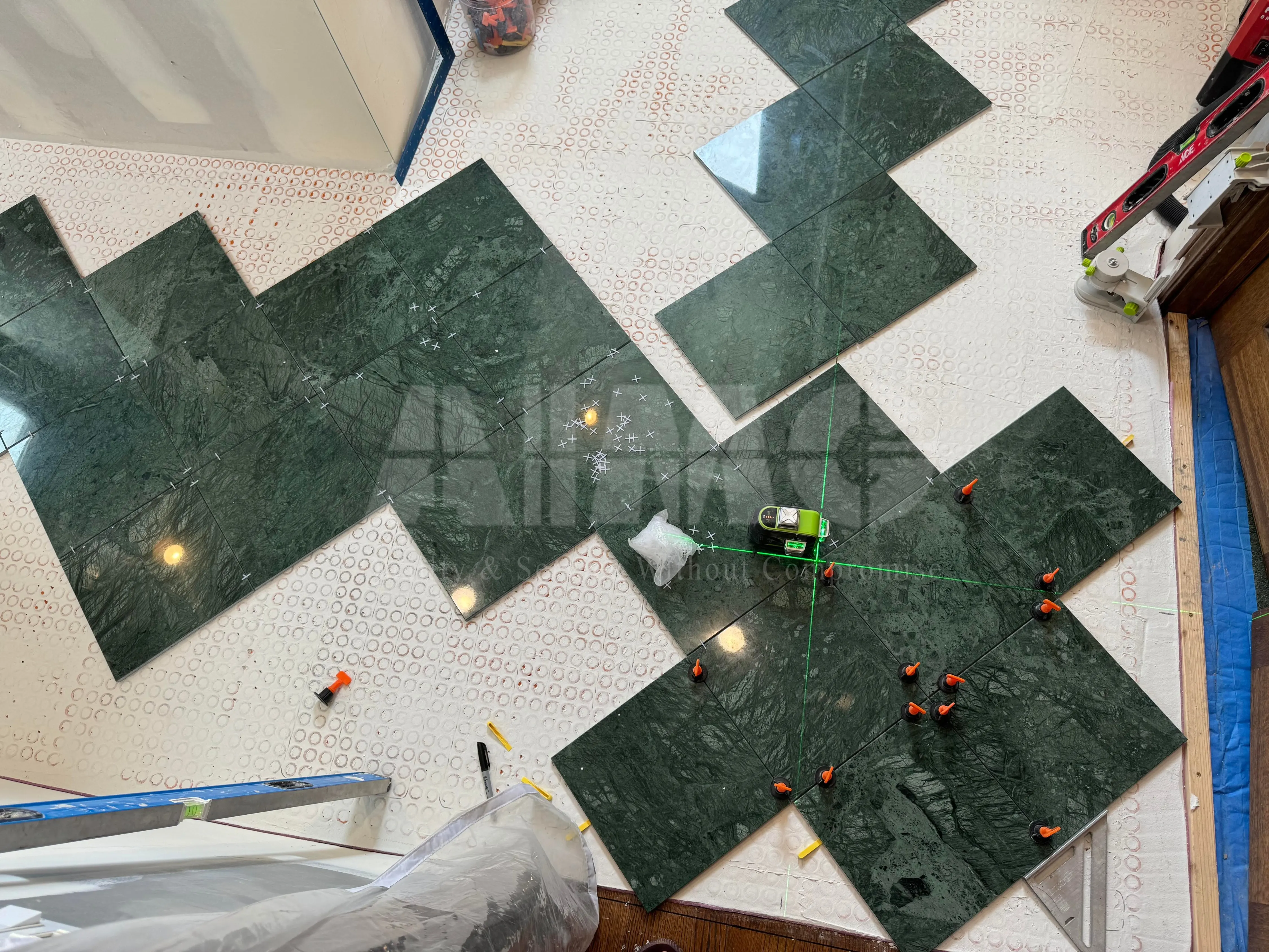 Premium green marble floor tiles by Aravali Marbles being installed, featuring polished emerald-green natural stone with rich veining for luxury residential and commercial flooring.