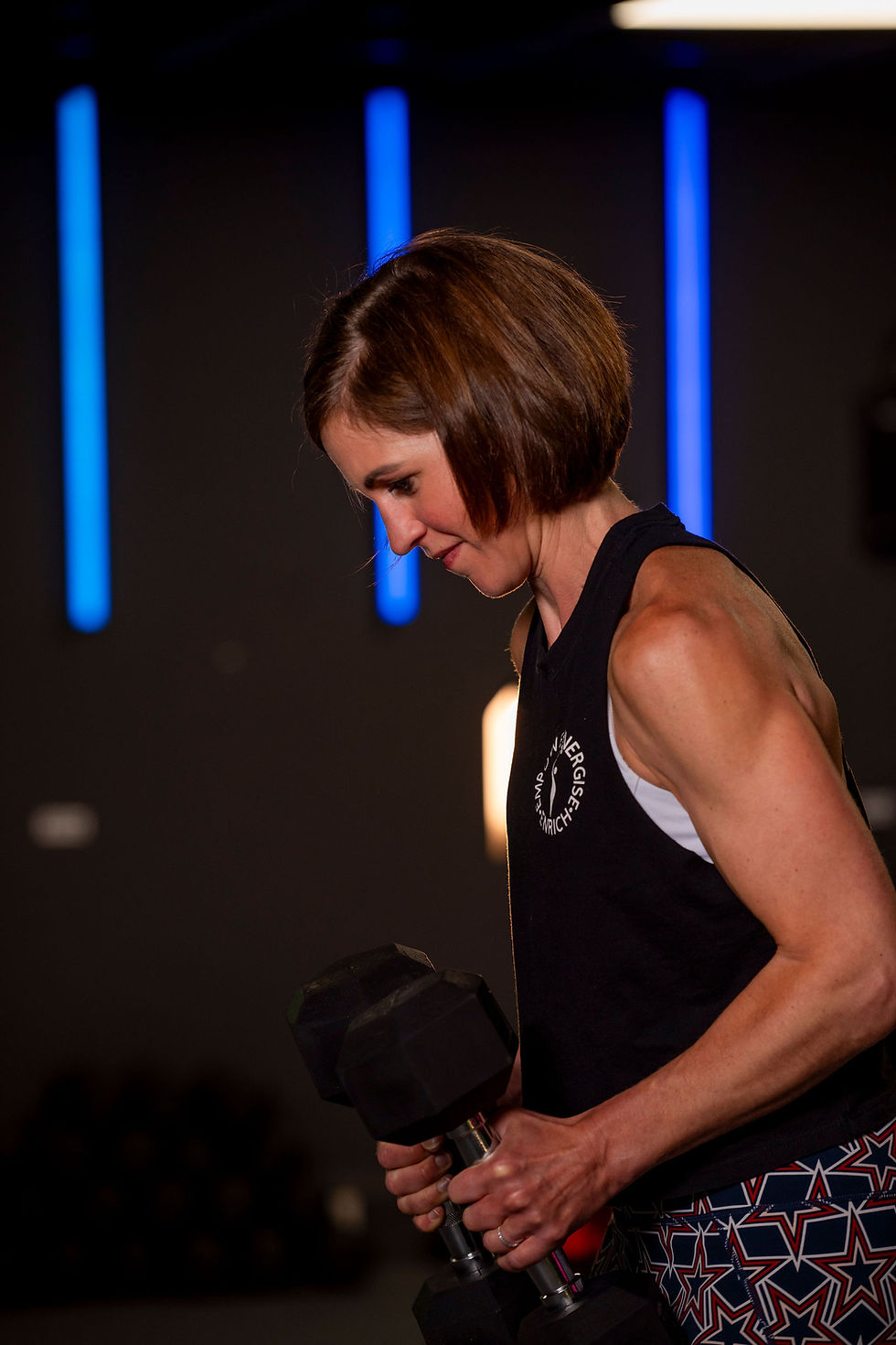 Woman lofting weights in gym setting.