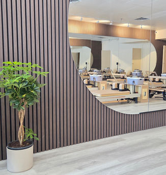 Curved mirrors and wood slat paneling in a modern reformer Pilates studio, Flow and Form Pilates in Richmond Hill, Ontario — reformer Pilates classes serving Thornhill, Markham, and York Region