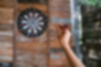 A close-up image of someone holding a dart aiming at the dartboard.