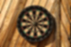 A dart board made of cork material at a wooden table.