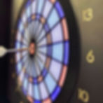 A dart arrow hitting the target of a colorful dartboard.