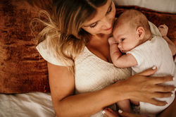 Mother and newborn son embracing on the bed