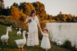 Mother and daughter in the park with ducks surrounding them